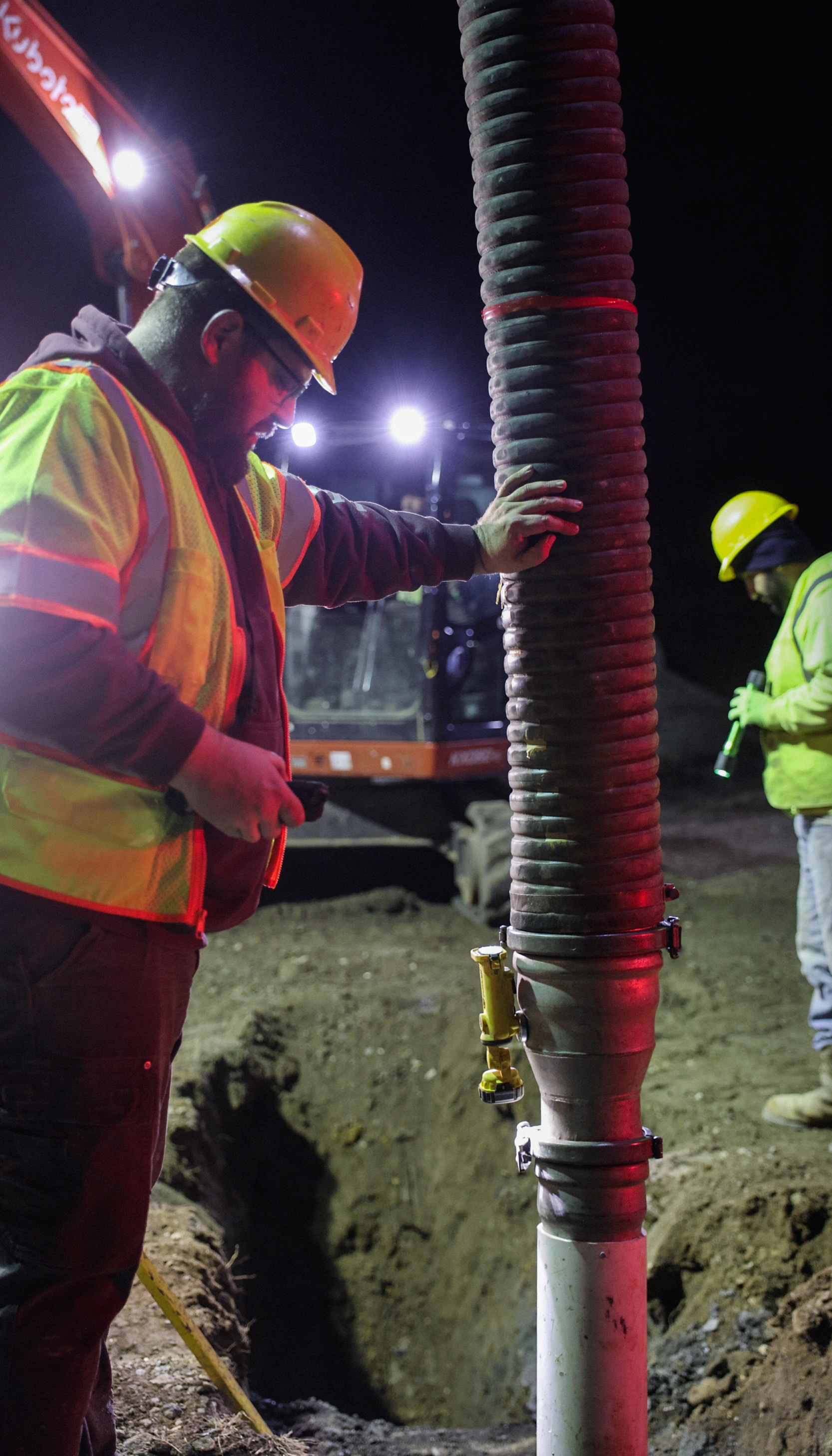 Worker installing drainage pipe at night